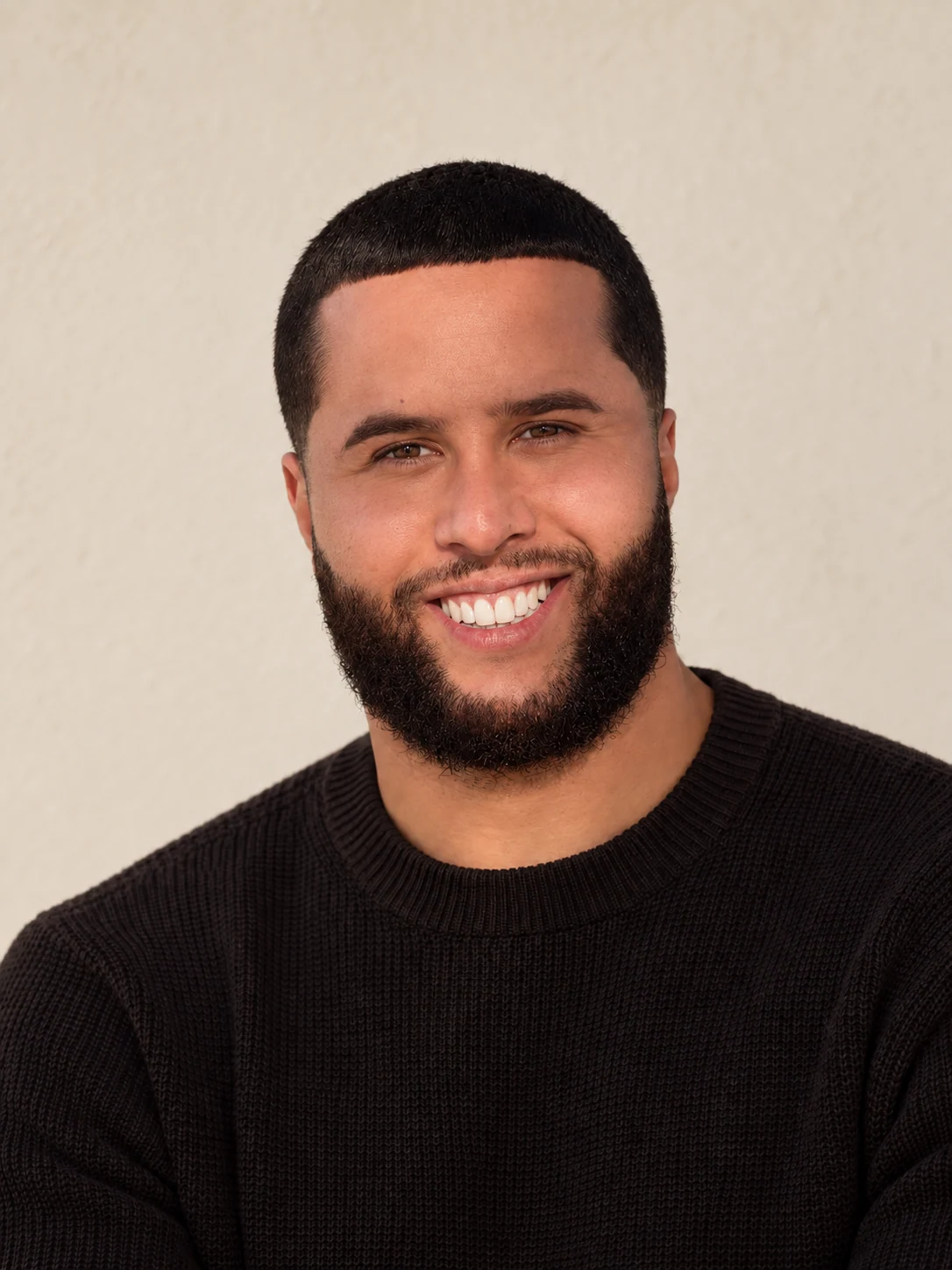 C-Money in a black knit sweater.